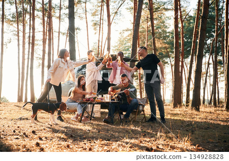 Doing cheers with bottles of beer. Group of friends are together in the forest 134928828