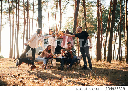Doing cheers with bottles of beer. Group of friends are together in the forest 134928829