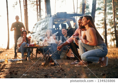 Time for preparing marshmallows on bonfire. Group of friends are together in the forest 134928866