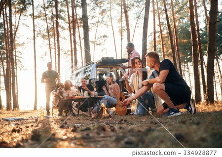 Couple sitting by bonfire. Group of friends are together in the forest Couple sitting by bonfire. Group of friends are together in the forest 134928877