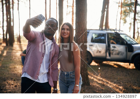 Taking selfie. Black man and white woman as couple are in the forest Taking selfie. Black man and white woman as couple are in the forest 134928897