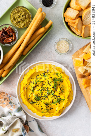 Gather around a colorful charcuterie board featuring turmeric hummus, cheese, nuts, and olives. This delightful spread invites friends to share tasty bites and enjoy each other company Gather around a colorful charcuterie board featuring turmeric hummus, cheese, nuts, and olives. This delightful spread invites friends to share tasty bites and enjoy each other company 134928945