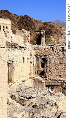 Cliffside Village With Ancient Dwellings, Archaeologist Surveys Historic Adobe Village On Elevated Cliffside, Panoramic Scene Of Ancient Adobe Homes Built On Steep Hillside With Erosion Features 134929237
