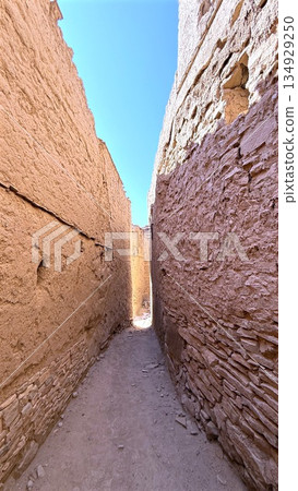Traveler Meanders Sunny Slender Street, Bright Corridor Bordered By Tall Adobe Buildings, Alley Bathed In Sunlight Where Explorer Navigates Through Narrow Passageway Surrounded By Towering Adobe Walls Traveler Meanders Sunny Slender Street, Bright Corridor Bordered By Tall Adobe Buildings, Alley Bathed In Sunlight Where Explorer Navigates Through Narrow Passageway Surrounded By Towering Adobe Walls 134929250