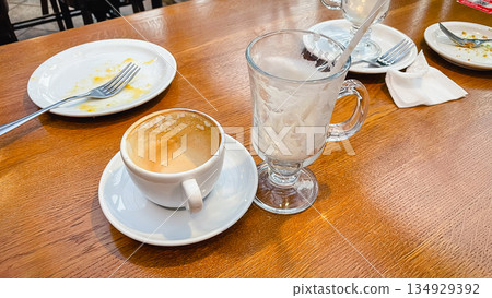 Empty coffee cup and glass mug with dirty plates on a wooden table after breakfast in a cafe 134929392
