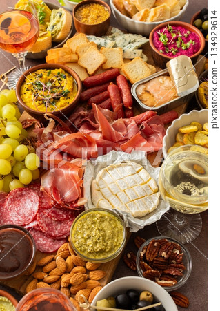 Taste a variety of flavors with this charcuterie board filled with cheese, sausages, hummus, nuts, and fresh sandwiches, perfect for any gathering 134929614