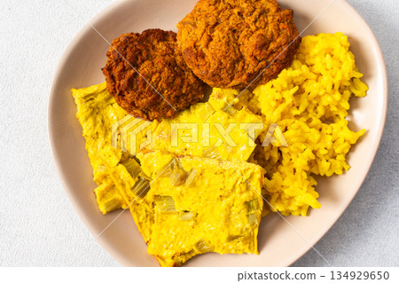 Colorful bowl of rice with rhubarb fried eggs, baked sweet potato, cauliflower, zucchini, and meat fritters alongside a fresh salad. Enjoy a nutritious and flavorful meal 134929650