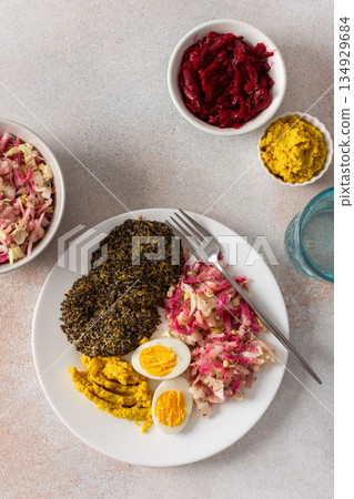 A nutritious breakfast featuring quinoa pancakes, fresh cabbage, radish, mung bean sprouts, boiled eggs, hummus, and roasted beets, perfect for a balanced start to your day 134929684