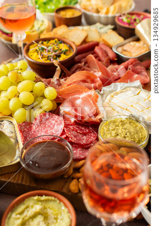 Gathered around a beautifully arranged charcuterie board filled with assorted cheeses, delicious sausages, creamy hummus, and fresh grapes. Perfect for a small gathering 134929685