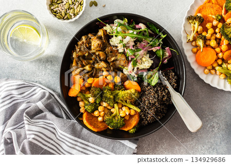 A nutritious breakfast bowl with black quinoa, avocado, roasted chicken, sweet potatoes, zucchini, and broccoli, paired with a fresh salad of cabbage, radish, chia, and sesame seeds 134929686