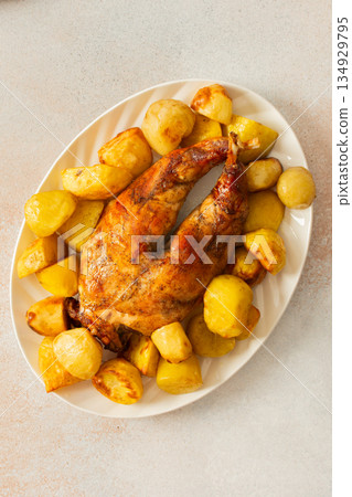 A beautifully presented dish features a whole baked rabbit surrounded by tender, golden-roasted potatoes. This comforting meal is perfect for family gatherings or special occasions. 134929795