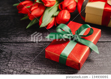 Red tulip bouquet with gift boxes. Easter or birthday holiday black background. 134930091