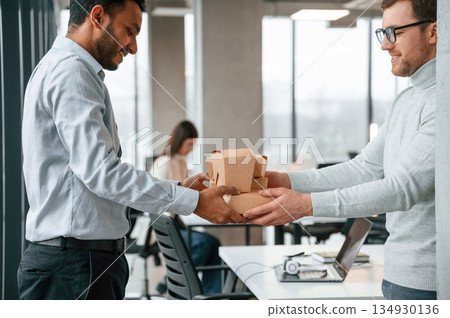 Taking the paper eco boxes. Men and woman are working in the office together 134930136