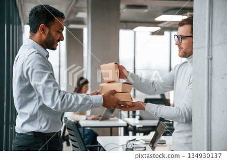Delivery in the paper eco boxes. Men and woman are working in the office together Delivery in the paper eco boxes. Men and woman are working in the office together 134930137