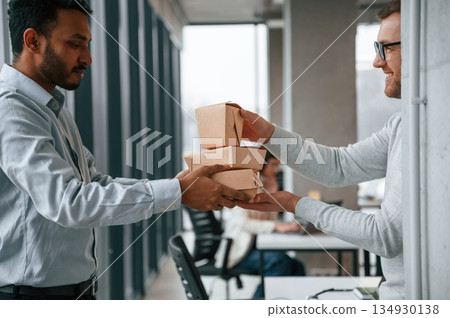 View from the side. Holding paper eco boxes. Two men are working in the modern office together 134930138