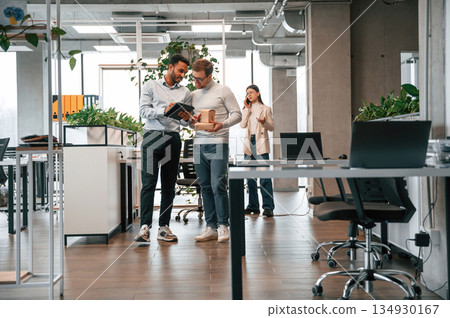 Holding eco boxes and tablet. Men and woman are working in the office together 134930167