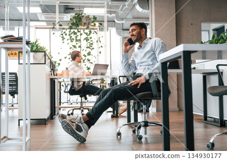 Taking a break. Using smartphone. Men and woman are working in the office together Taking a break. Using smartphone. Men and woman are working in the office together 134930177