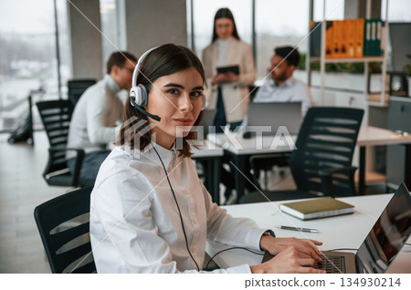 Woman is working by laptop. Four people are working in the office together Woman is working by laptop. Four people are working in the office together 134930214