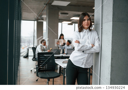 Gorgeous woman is in the front of her colleagues. Four people are working in the office together Gorgeous woman is in the front of her colleagues. Four people are working in the office together 134930224