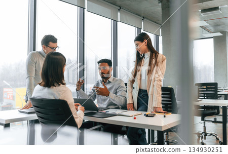 By the table. Four people are working in the office together By the table. Four people are working in the office together 134930251