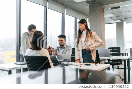 By the table. Four people are working in the office together By the table. Four people are working in the office together 134930252