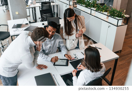 By the table. Four people are working in the office together By the table. Four people are working in the office together 134930255