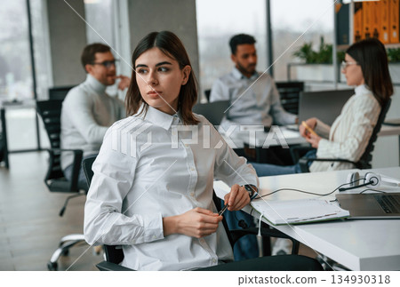 Woman is working by laptop. Four people are working in the office together Woman is working by laptop. Four people are working in the office together 134930318