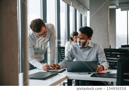 Guys are talking with each other. Men and woman are working in the office together Guys are talking with each other. Men and woman are working in the office together 134930358
