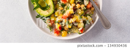 A vibrant vegetarian salad featuring boiled millet, chickpeas, fresh vegetables, and avocado, drizzled with olive oil for a delicious and healthy meal, banner A vibrant vegetarian salad featuring boiled millet, chickpeas, fresh vegetables, and avocado, drizzled with olive oil for a delicious and healthy meal, banner 134930436