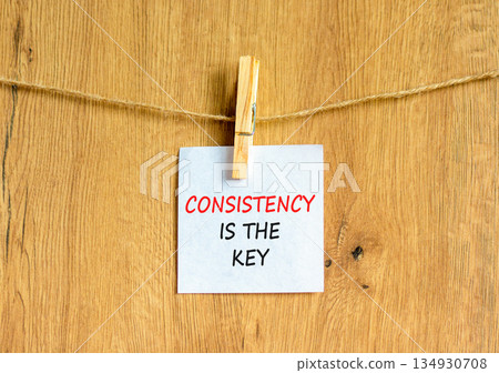 Consistency is the key symbol. Concept words Consistency is the key on beautiful white paper on wooden clothespins. Beautiful wooden background. Business consistency is the key concept. Copy space. 134930708