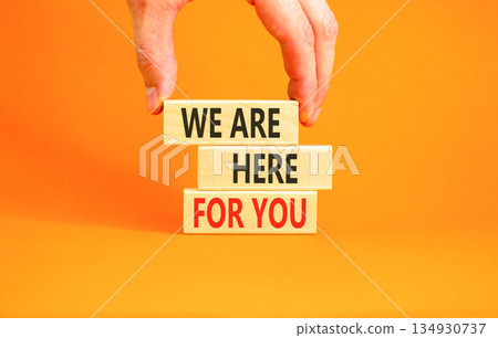 Support, help and we are here for you symbol. Concept words We are here for you on beautiful blocks. Beautiful orange background. Businessman's hand. Business we are here for you concept. Copy space. 134930737