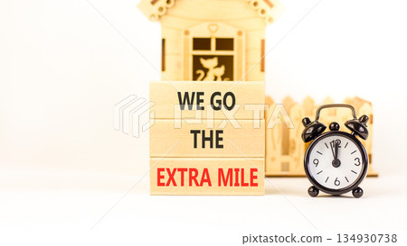 Support, help we go the extra mile symbol. Concept words We go the extra mile on beautiful wooden blocks. Beautiful white background. Black alarm clock. Business we go extra mile concept. Copy space. 134930738
