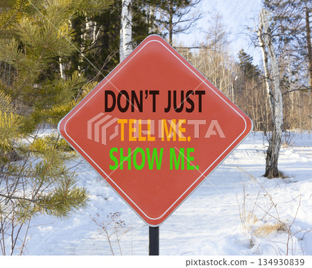 Tell or show symbol. Concept words Do not just tell me, show me on beautiful red road sign. Beautiful winter forest background. Business tell or show concept. Copy space. 134930839