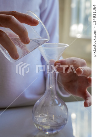 Hands Pouring Liquid into Glass Flask Vertical Hands Pouring Liquid into Glass Flask Vertical 134931364