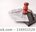 A gavel stack of US currency, a wallet, and a pen on white background. 134931520