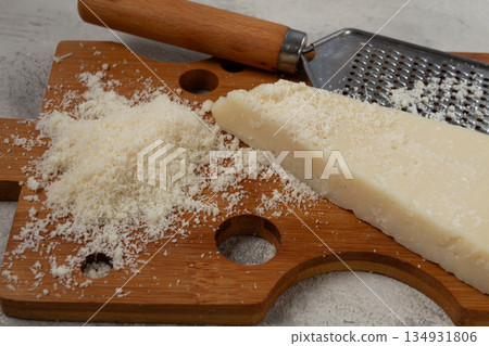 Freshly sliced and grated cheese, parmesan cheese, on a wooden chopping board, rustic style, no people Freshly sliced and grated cheese, parmesan cheese, on a wooden chopping board, rustic style, no people 134931806