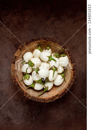 white mini eggplant, in a wooden bowl, on the table, close-up. white mini eggplant, in a wooden bowl, on the table, close-up. 134931815