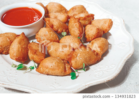 Fried mini chebureks, with sauce, on a decorative plate, hard light, no people, Fried mini chebureks, with sauce, on a decorative plate, hard light, no people, 134931823