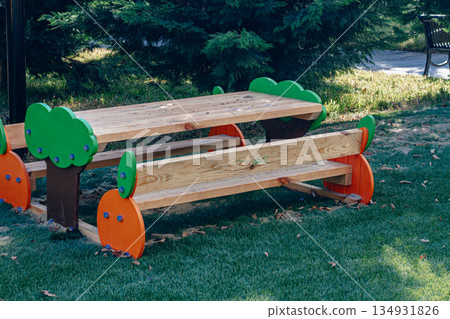 Colorful wooden picnic table in a green park on a sunny day with playful design elements 134931826