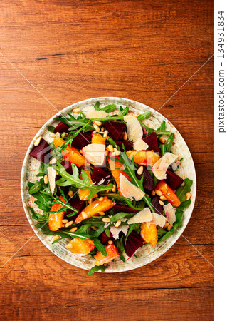 Fresh salad with beetroot, orange, and pine nuts served on a table in a casual dining setting 134931834