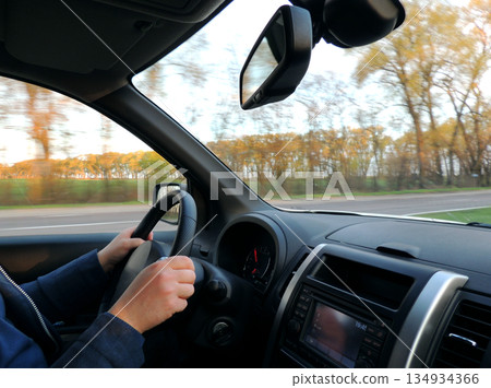 Optimal position of man hands on the steering wheel in fast moving vehicle 134934366