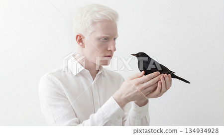 Beautiful albino model holding a black crow in hands 134934928