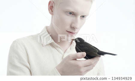 Beautiful albino model holding a black crow in hands 134934929