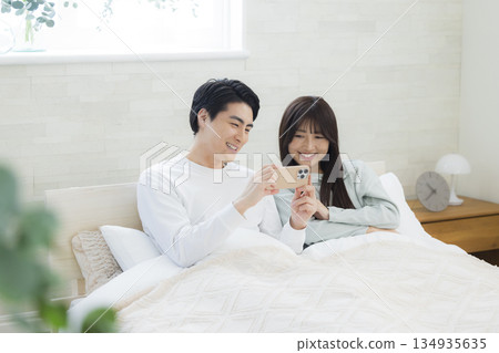 夫婦在床上看智慧型手機 134935635