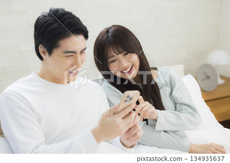 Couple looking at smartphone in bed Couple looking at smartphone in bed 134935637