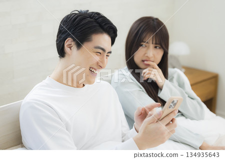 Couple looking at smartphone in bed 134935643