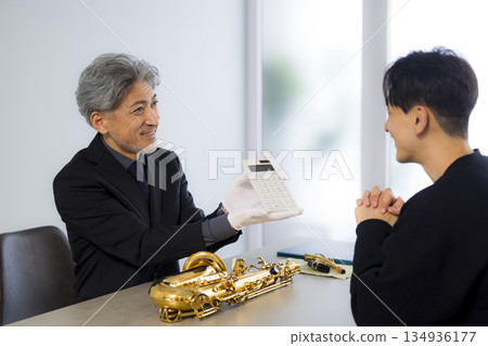 一名男子正在鑑定一支薩克斯風 134936177