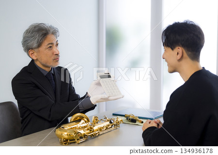 一名男子正在鑑定一支薩克斯風 134936178