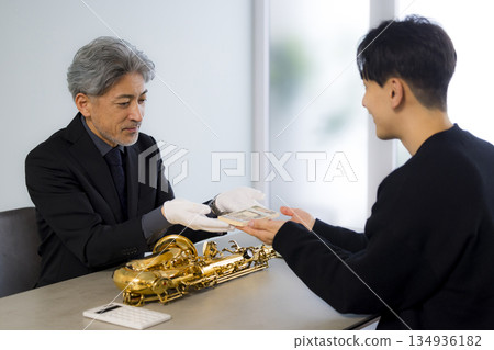 一名男子正在鑑定一支薩克斯風 一名男子正在鑑定一支薩克斯風 134936182