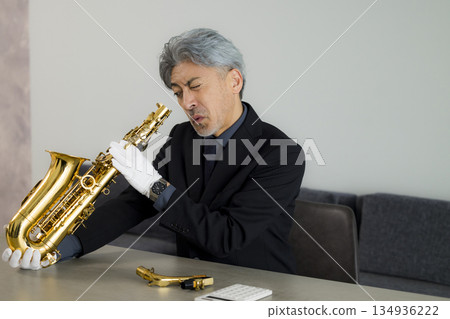 一名男子正在鑑定一支薩克斯風 134936222